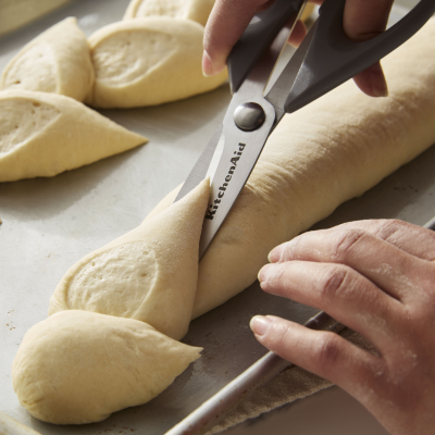 Person cutting bread dough with scissors