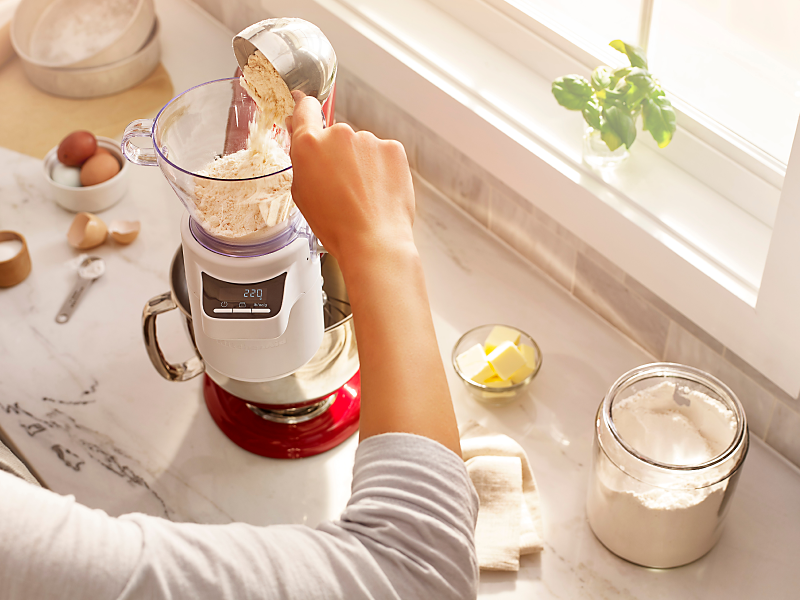 Person adding flour into a KitchenAid® stand mixer