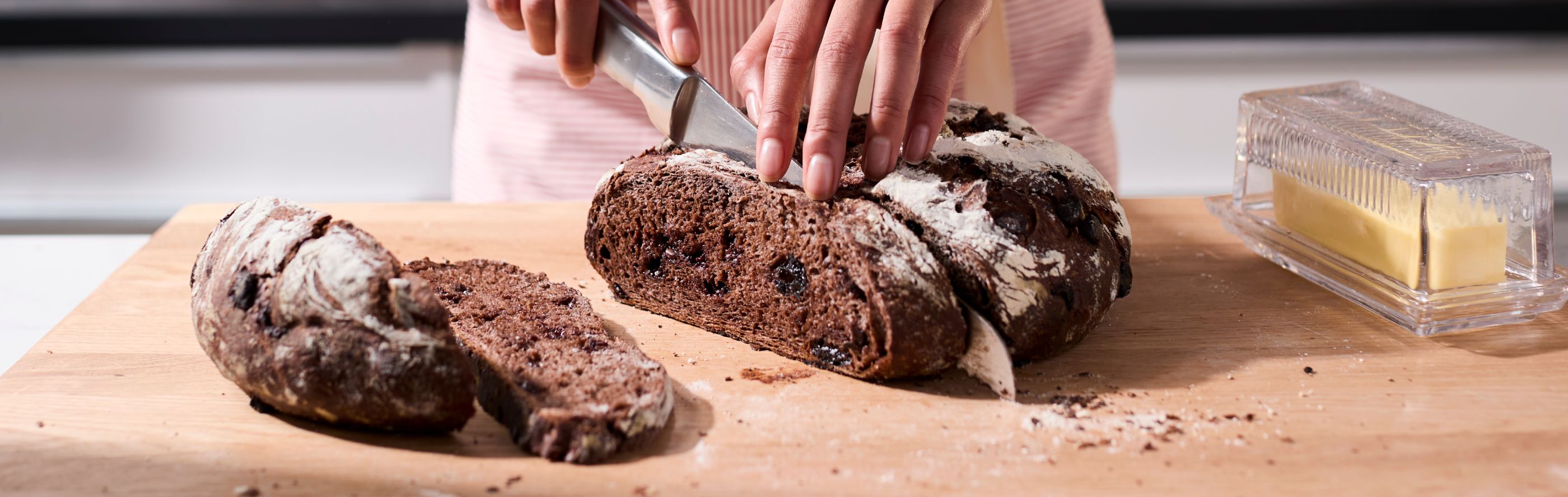 Person slicing dark brown bread