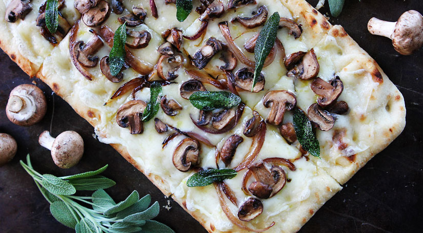 Flatbread pizza topped with cheese, mushrooms and herbs