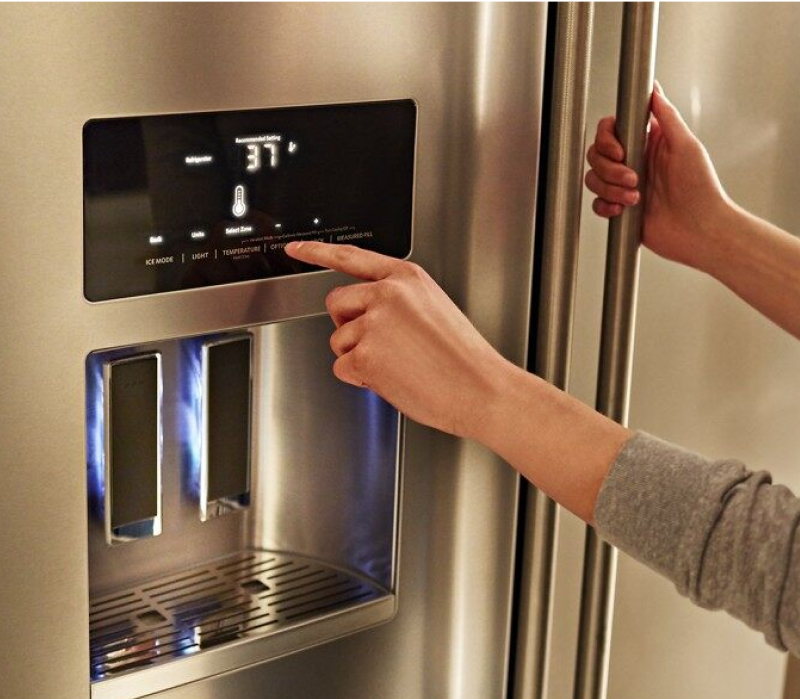 A person engaging with the touchscreen controls on the KitchenAid® French Door Bottom Mount Refrigerator.