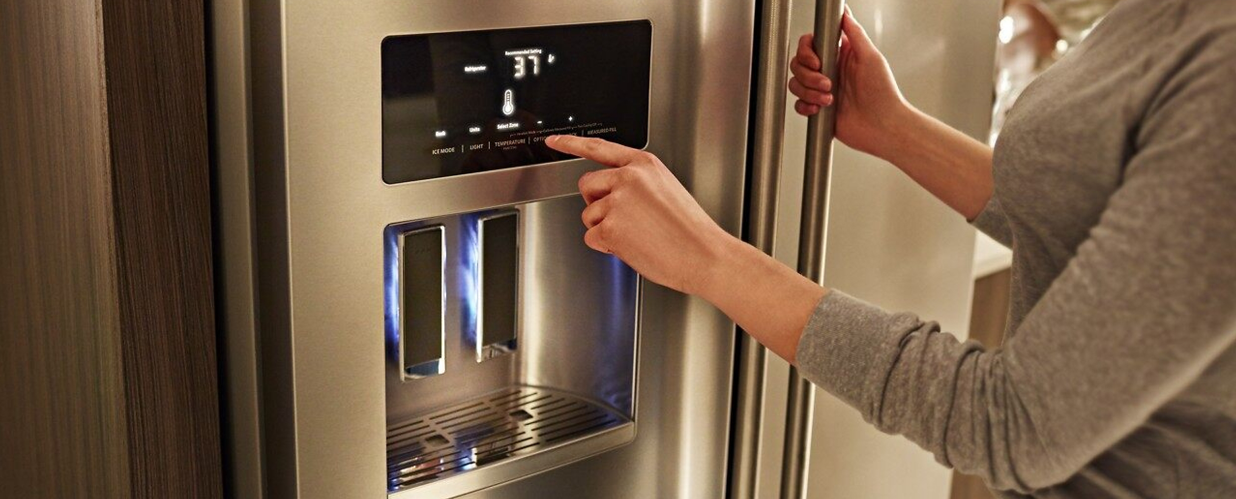 A person engaging with the touchscreen controls on the KitchenAid® French Door Bottom Mount Refrigerator.