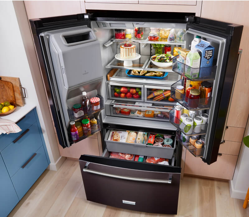 A fully loaded KitchenAid® French Door Bottom Mount Refrigerator with the doors and drawers open.
