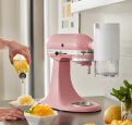 An Artisan® Series Stand Mixer in Dried Rose with the Shave Ice Attachment making shave ice mango desserts.