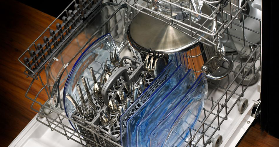 The lower rack of a Maytag dishwasher. The rack is filled with plates, a cutlery tray and a pot