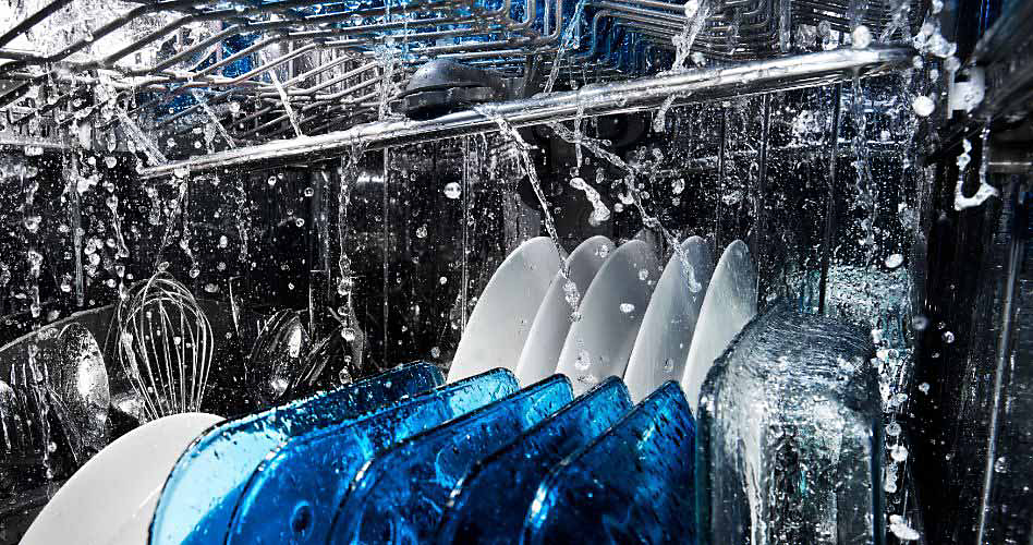 A Maytag dishwasher in the middle of a wash cycle. Plates, utensils and more are being cleaned