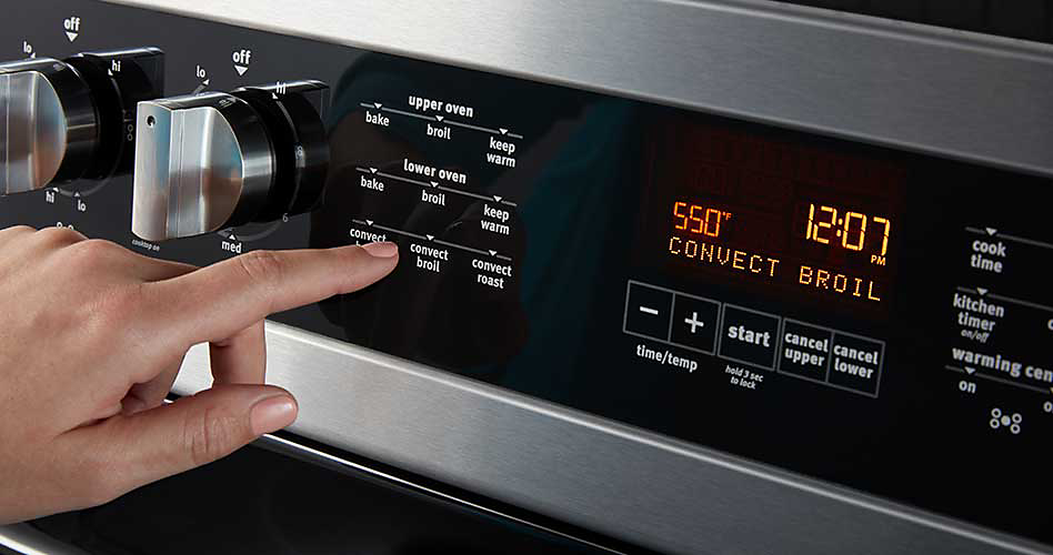 Someone pushes a button on the controls of a Maytag oven. The display reads, "550, convect broil and 12:07"