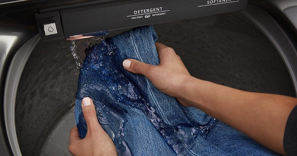 A person washing an item of denim clothing in the pretreating station of a washing machine.