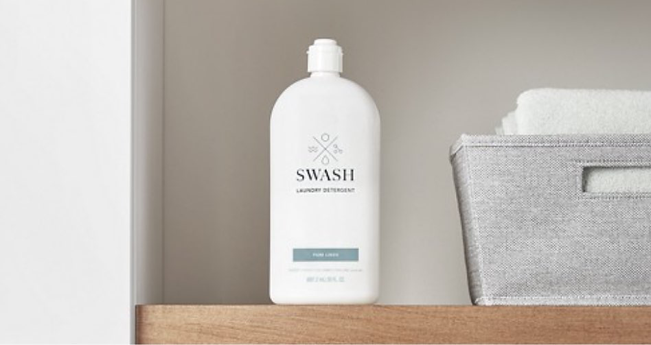 a bottle of Swash liquid laundry detergent on a wooden shelf. Next to it is a silver basket.