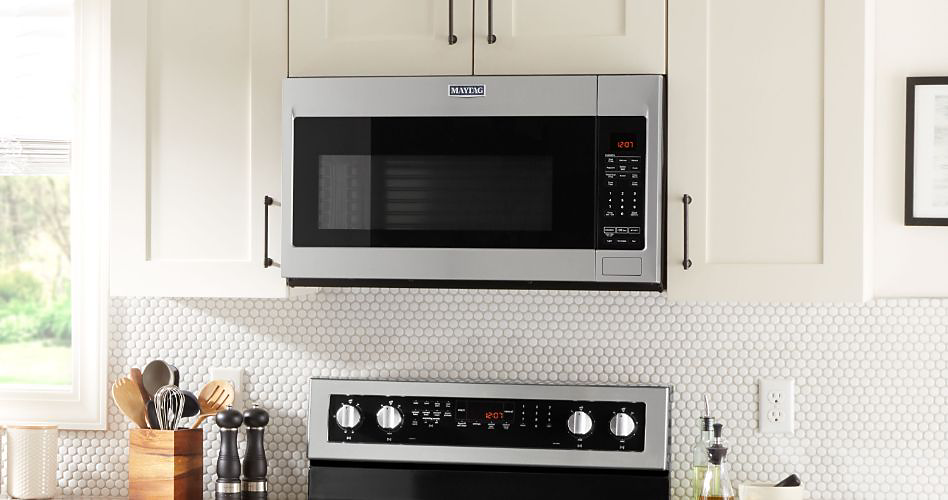 A kitchen with a Maytag over-the-range microwave and a Maytag oven. On the counter next to the oven are a container of kitchen utensils, salt and pepper shakers and two oil bottles