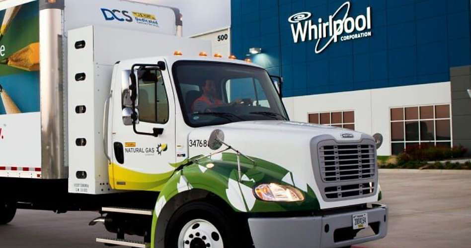 A truck in front of a building with the Whirlpool logo on the facade.