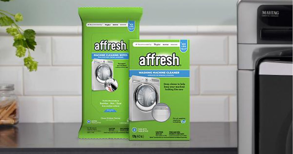 Two packs of affresh cleaner, one large and one small, next to a washing machine and in front of white tile backsplash. Next to them is a plant