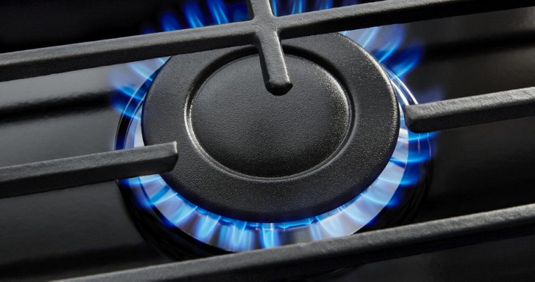 A gas cooktop burner with blue flame