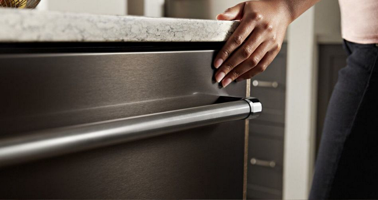  A hand touches the corner above the towel bar on a Maytag Stainless Steel Dishwasher.