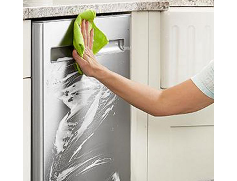  A person wipes away the cleaner on a Maytag Stainless Steel Dishwasher.