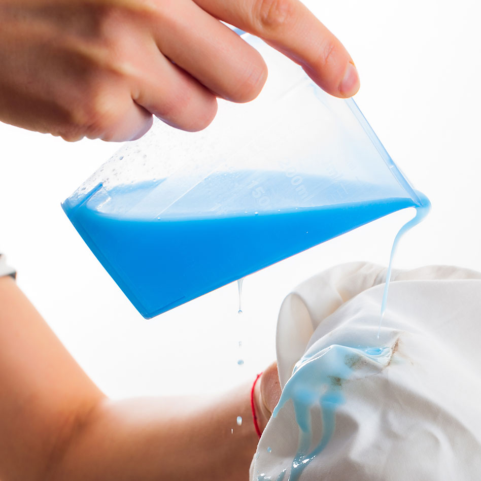 Blue laundry detergent being poured onto a cloth