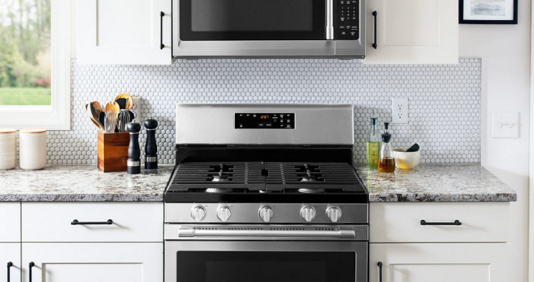 A Maytag Oven with an Over-the-Range Microwave. On the counters are a container of kitchen utensils, salt and pepper shakers, oil containers and a white bowl.
