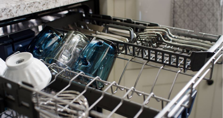 The upper rack of a Maytag Dishwasher. On the rack are small bowls, glasses, a whisk and cutlery.