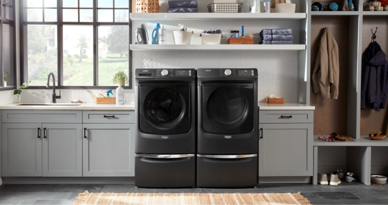 A laundry room featuring a black front loading washer and dryer on pedestals.