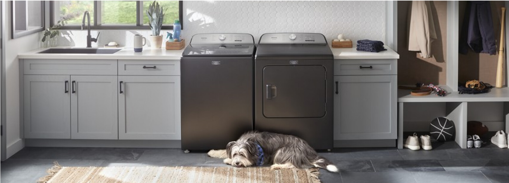 A Maytag® washer and dryer in a laundry room with white cabinets and dog laying on the floor 