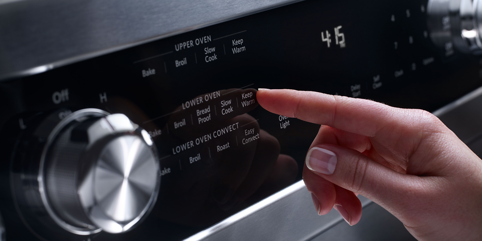 A person selects an oven setting from a range's control panel.