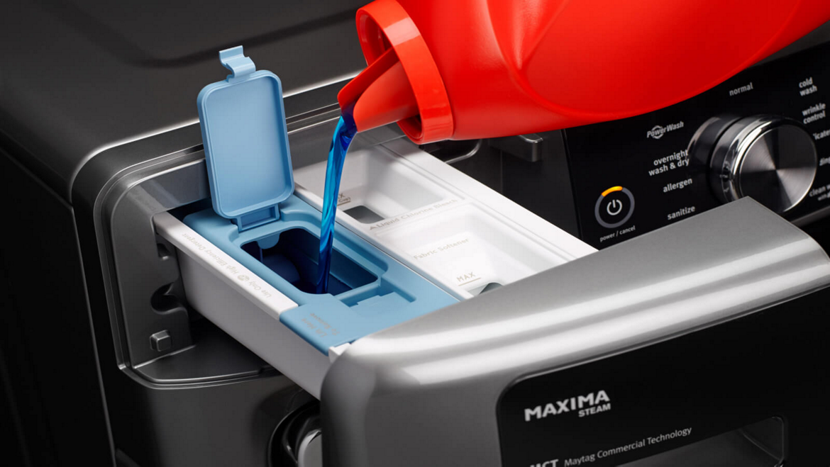 Filling a Maytag® washing machine dispenser with detergent.