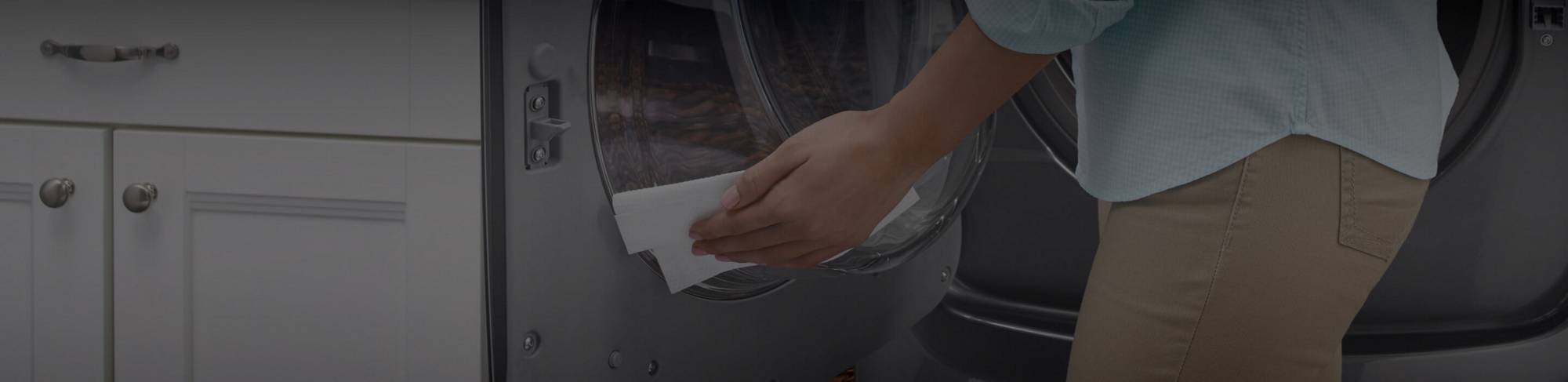 A woman cleaning the inside of a Maytag® front-load washer.