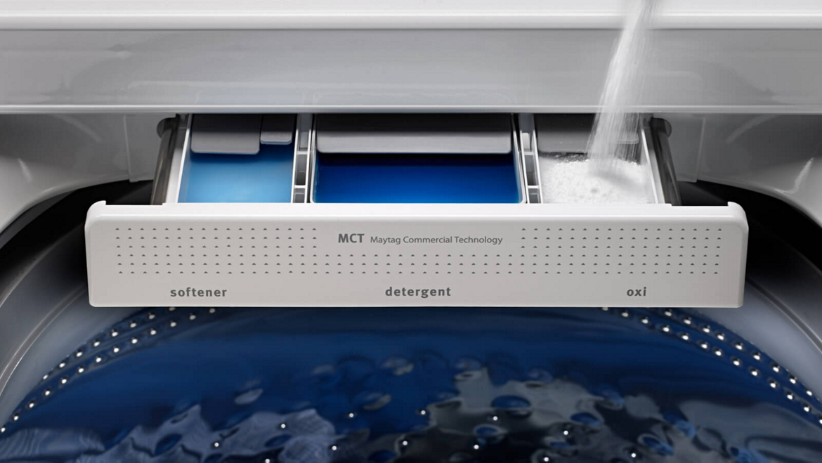 Filling a Maytag® washing machine dispenser with detergent.