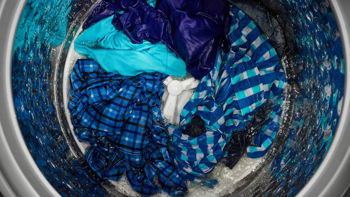 Maytag® top-load washer filled with blue clothes.
