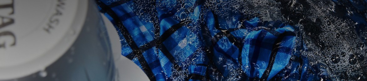 A blue shirt in Maytag® top-load washer that's filled with water.