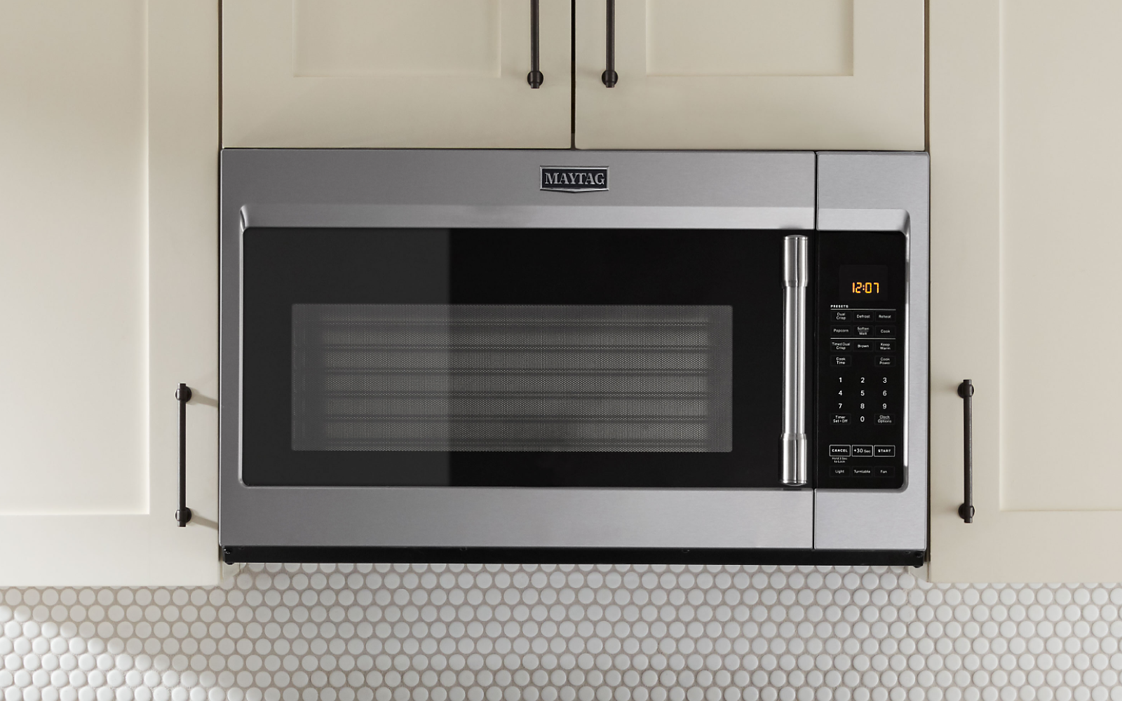 Maytag® over-the-range microwave between white cabinets