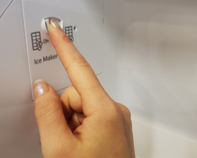  A finger pressing an ice maker button