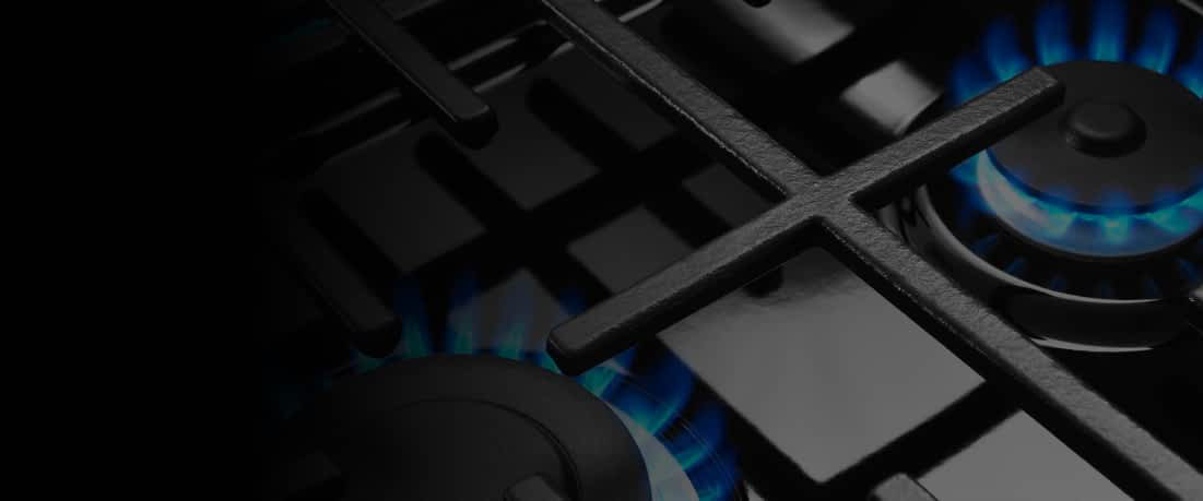 A gas cooktop with a burner ignited.