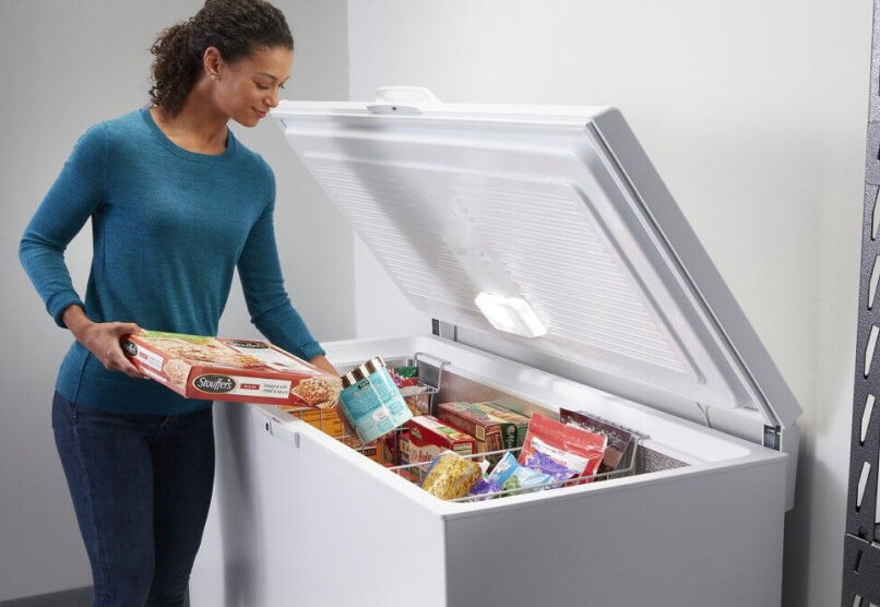 A woman putting frozen food into a Maytag® chest freezer.