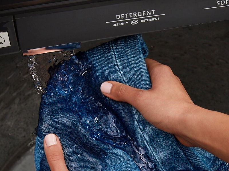Hands pre-treating denim with built-in water faucet
