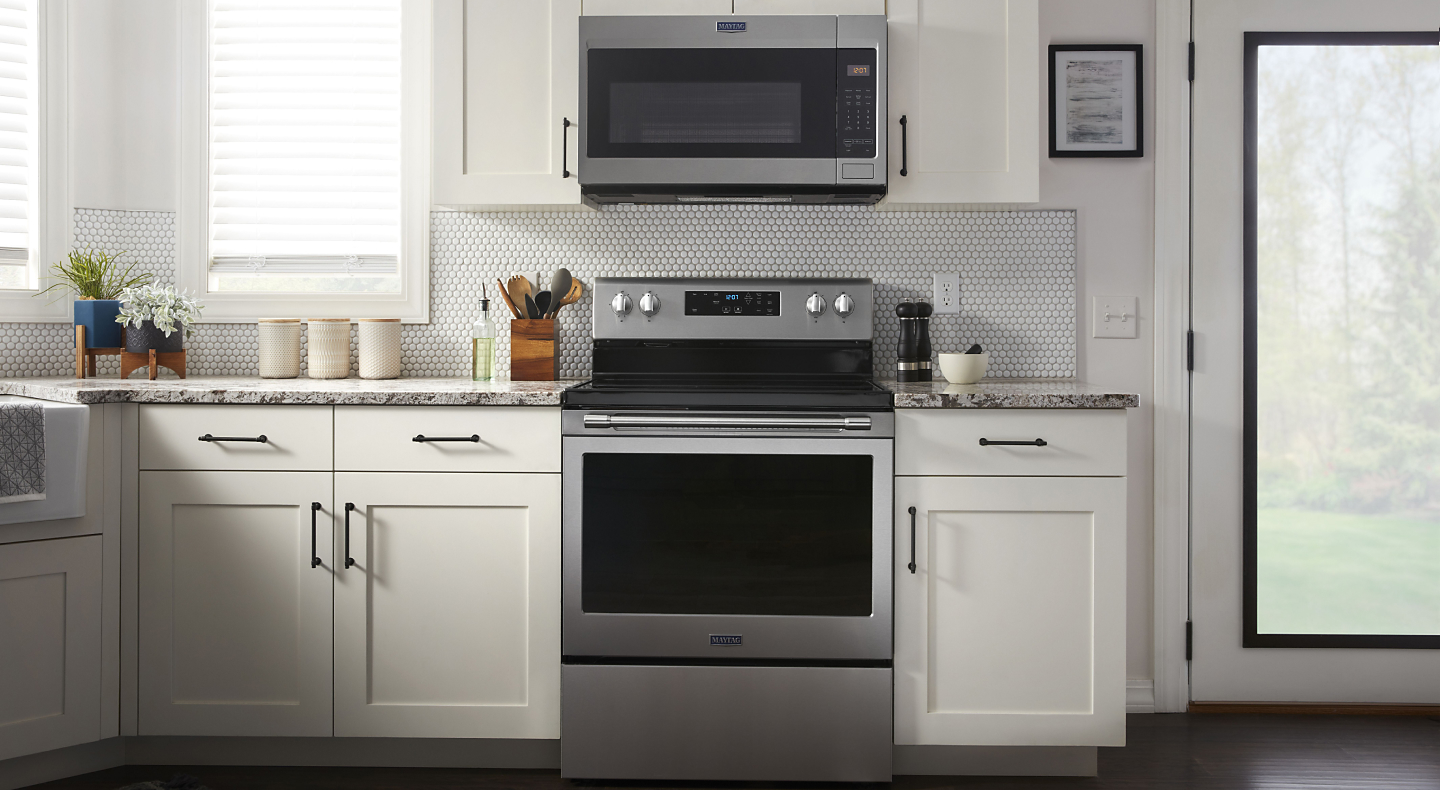 Stainless steel Maytag® over-the-range microwave and electric range in white cabinetry