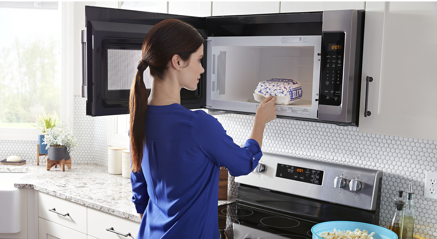 Person removing popcorn from an over-the-range microwave