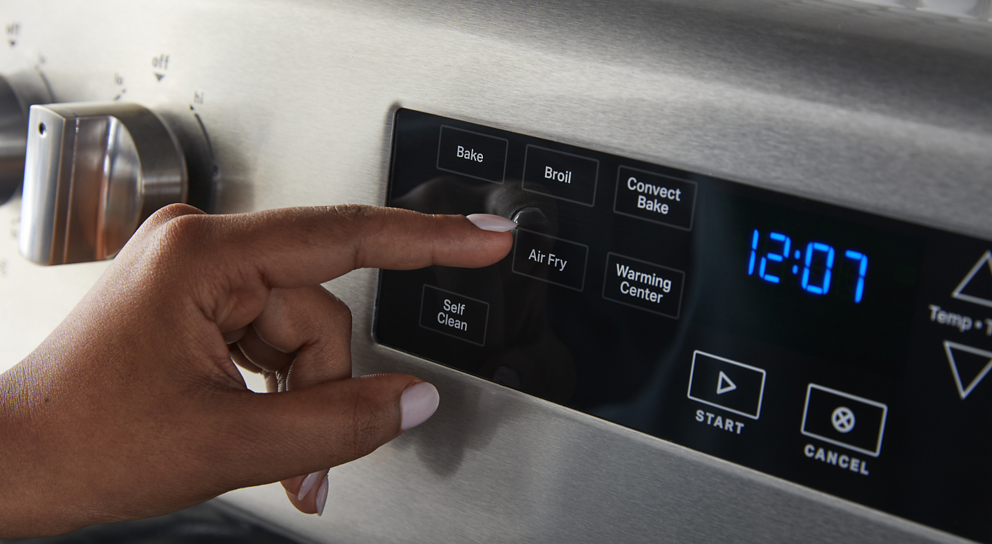 Finger pressing the Air Fry button on a stainless steel oven