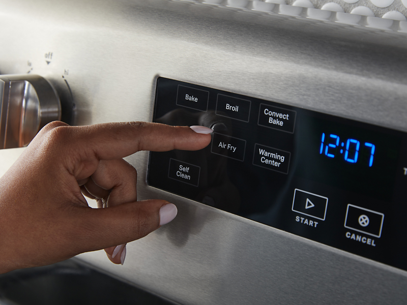 Finger pressing the Air Fry button on a stainless steel oven