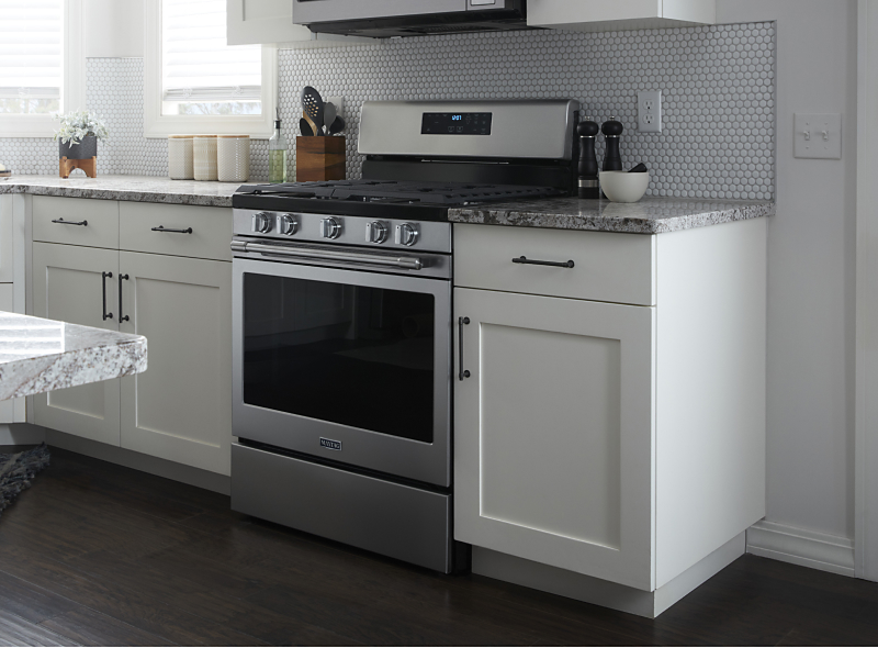 Stainless steel KitchenAid® gas range surrounded by white cabinets