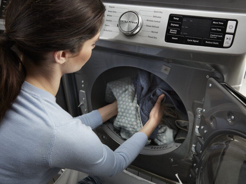A woman unloading laundry from a Maytag® gas dryer