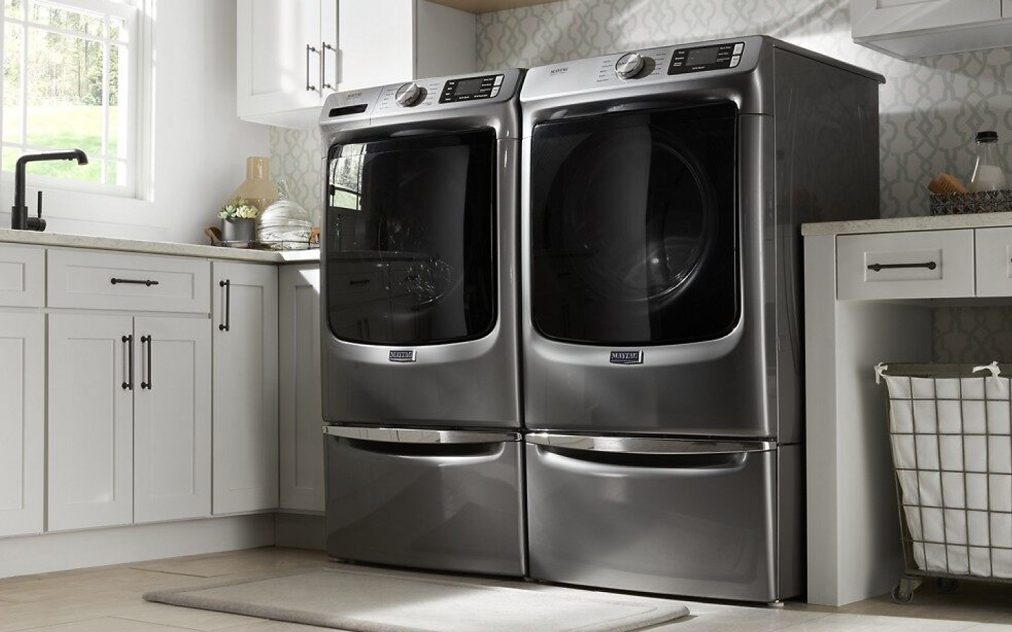 Gray MaytagⓇ front-load washer and dryer pair on pedestals 