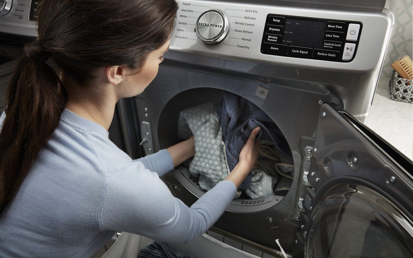 Woman removing clothes from gray MaytagⓇ dryer