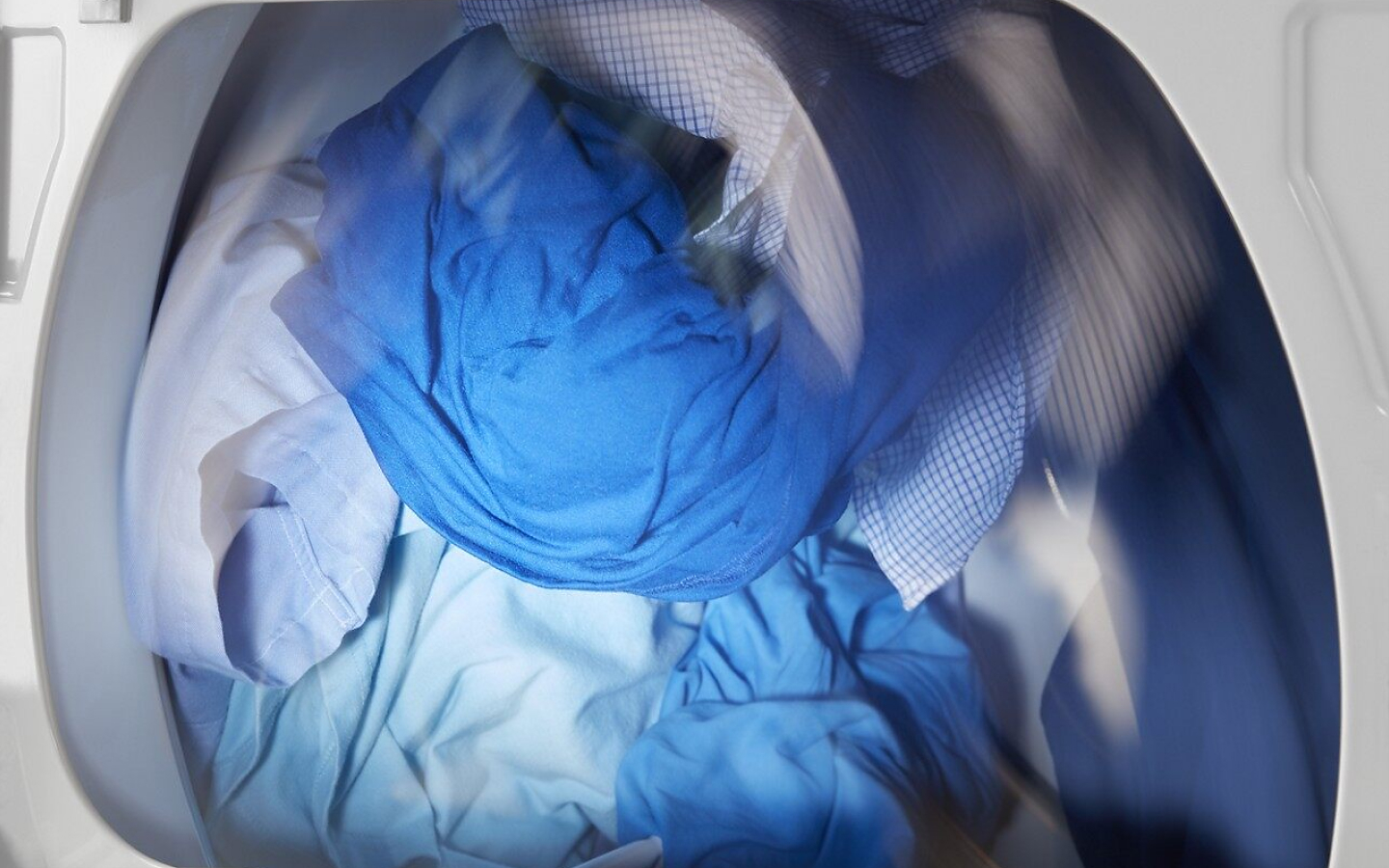 Blue clothes rotating in white dryer