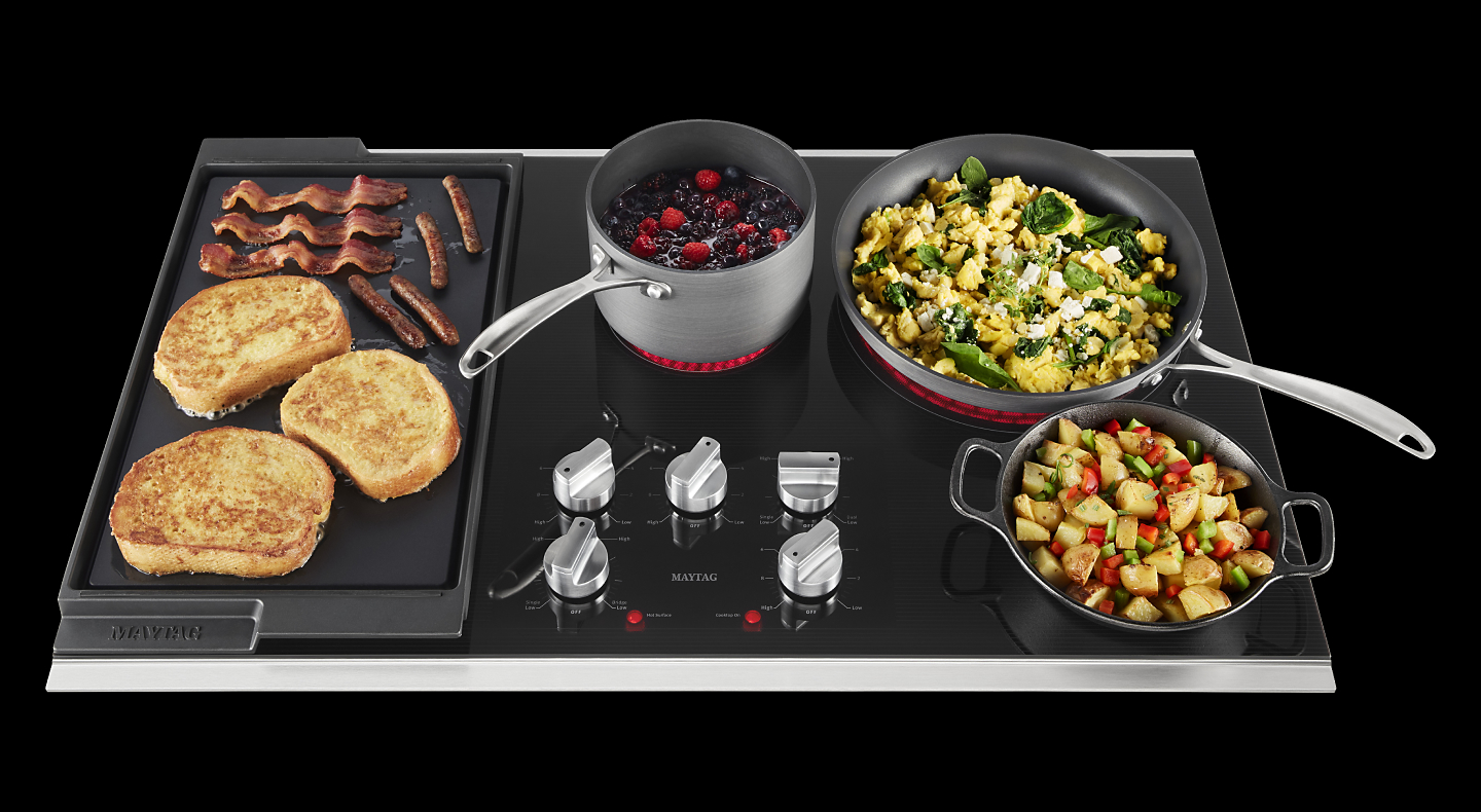 An electric cooktop cooking five different dishes at once