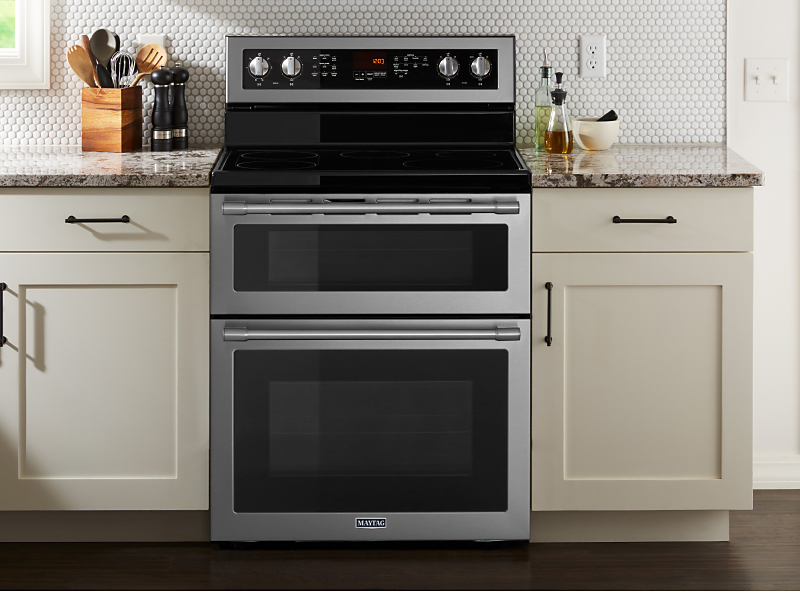 Maytag brand double oven in between white cabinetry 