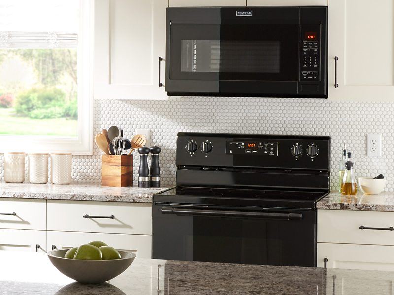 Black over-the-range microwave and range in kitchen with white cabinets