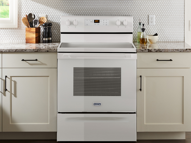 White Maytag brand oven in between white cabinetry 