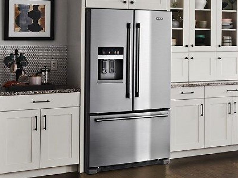 Stainless steel French door refrigerator from Maytag brand in kitchen with white cabinetry