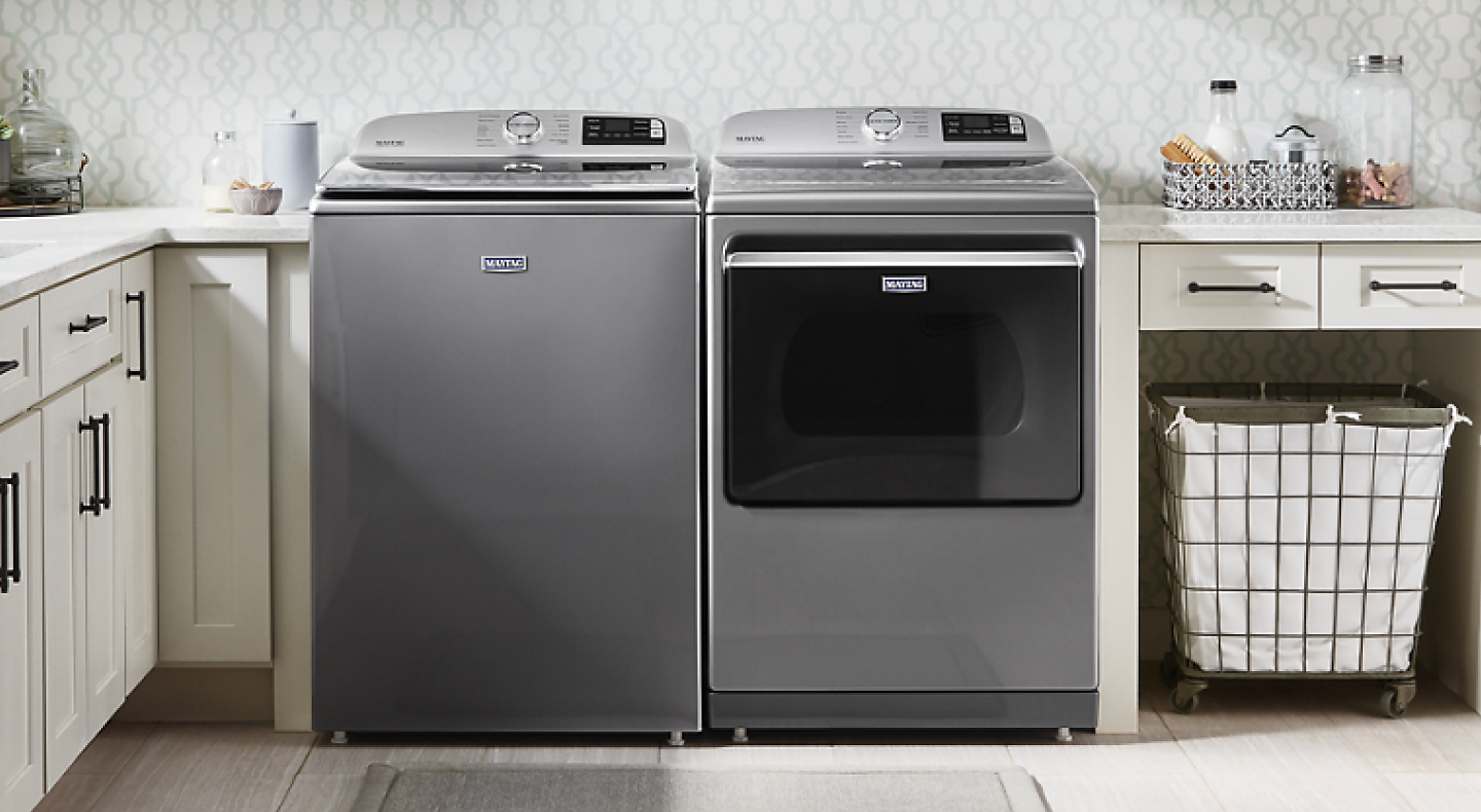 Gray top load Maytag® washer and dryer pair in off white laundry room cabinets